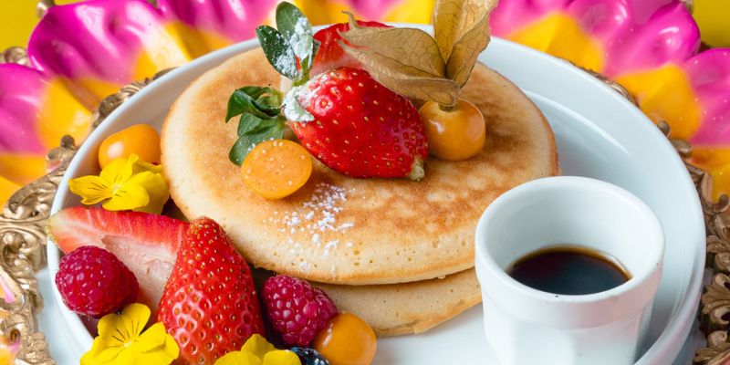 Torre de pancakes esponjosos servidos con frutas frescas de temporada, bayas y sirope de arce en Berry Brunch de Barcelona.